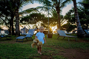 Wall Mural - Happy beautiful fashion kid, child, casually dressed, enjoying the sunrise on the beach in Mauritius