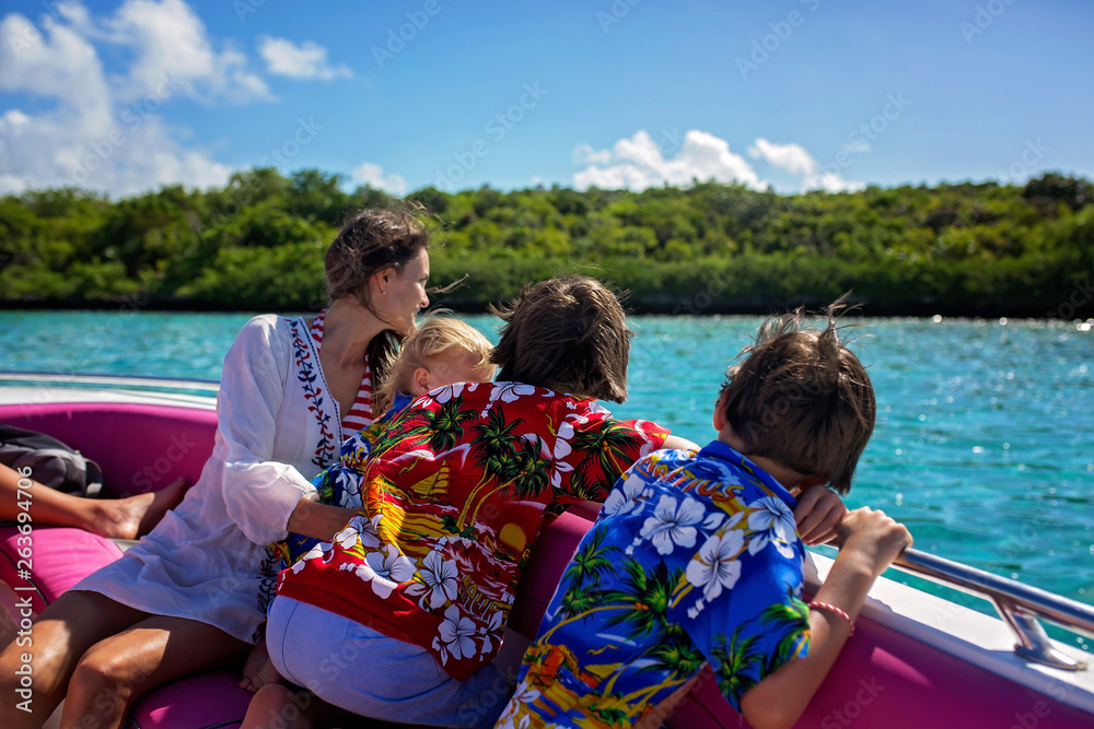 Happy beautiful fashion family, children and parents, dressed in hawaiian shirts, enjoying day trip with speed boat
