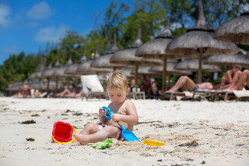 Wall Mural - Cute toddler baby boy playing with beach toys on tropical beach