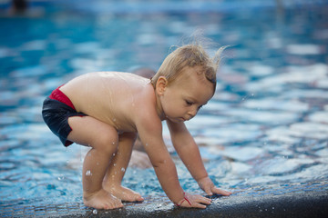 Adorable happy little child, toddler boy, having fun relaxing and playing in a pool on sunny day during summer vacation