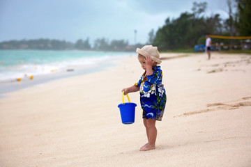 Wall Mural - Cute toddler baby boy playing with beach toys on tropical beach