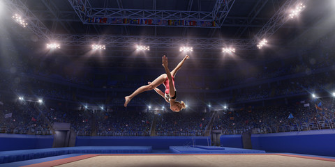 Wall Mural - Female athlete doing a complicated exciting jump trick in a professional gym. Girl perform stunt in bright sports clothes