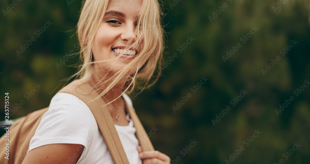 Portrait of a smiling woman explorer wearing a backpack - obrazy, fototapety, plakaty 