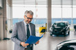 © cherryandbees - sales agent holding brochure in car dealership show room