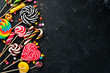 Colorful candies and lollipops. On a black stone background. Top view. free copying space.