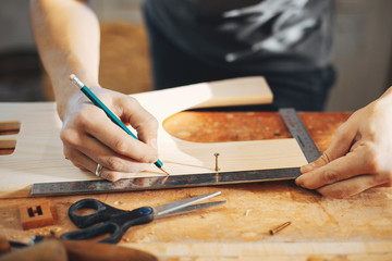 Wall Mural - A man carves a tree. The carpenter works in a studio. An engineer provides a tree shape