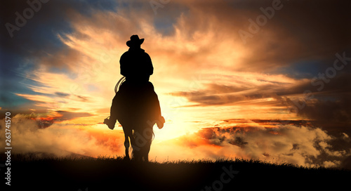 Cowboy on a horse at sunset Poster Mural XXL
