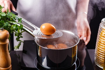 young woman in an gray apron boiled eggs