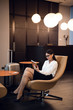 © romankosolapov - Confident businesswoman listening music on her tablet computer while sitting in chair in airport business lounge
