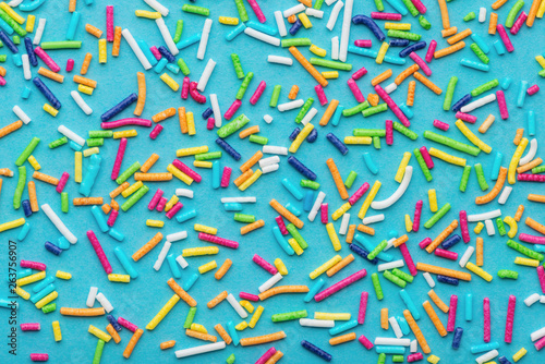 pattern of colorful sprinkles over blue background, festive decoration for ca...