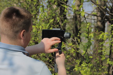 Wall Mural - A young man videotaping on a smartphone. Uses gimbal to get smooth shots. Controls the recording by touching the screen.