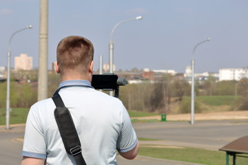 Wall Mural - A young man videotaping on a smartphone. Uses gimbal to get smooth footage. Closely watching the movie shooting.