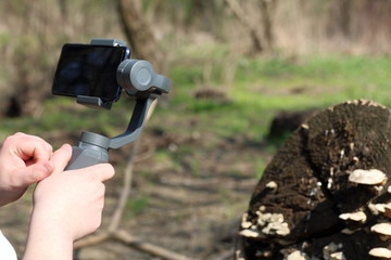 Wall Mural - A young man videotaping on a smartphone. Uses gimbal to get smooth footage. Closely watching the movie shooting.