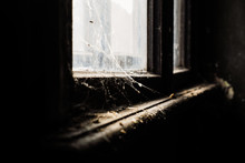 A Dirty, Dark Window In A Dark Room With Spider Webs And A Dirty Window Sill