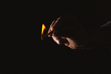 Burning match in the man's hand. Dangerous game with fire.