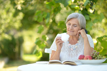 Wall Mural - Portrait of beautiful middle-aged woman sitting at the table with book