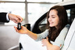 © Wellnhofer Designs - Hübsche junge Frau nimmt in den Autoschlüssel für ein neues Auto entgegen