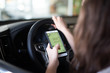 © Wellnhofer Designs - Frau hat ihr Handy wärend der Fahrt in der Hand und schreibt eine Nachricht
