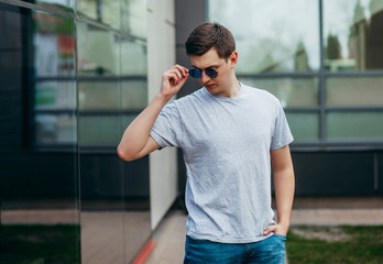 Wall Mural - A stylish man in a gray  T-shirt. Street photo