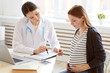 Portrait of female obstetrician consulting pregnant woman in doctors office, copy space