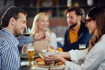 Poster - Multiethnic friends sitting at restaurant, drinking alcohol, chatting and having burgers for dinner.