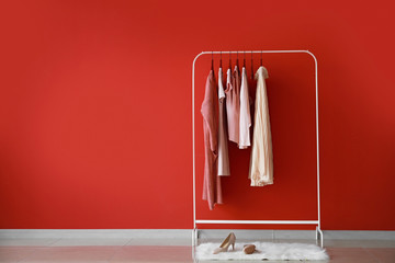 rack with stylish clothes near color wall
