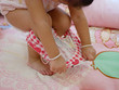 Little Asian baby girl, 25 months old, learning to take off short pants by herself - child development by allowing them to do things by themselves