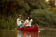 © Branko Starcevic/Stocksy - Family paddling red canoe in the river.