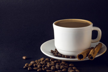 White cup of hot coffee and Cinnamon sticks isolated on black background.