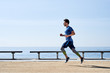 © guille Faingold/Stocksy - Strong athlete running on sunny embankment