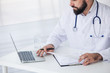© D'Action Images - Doctor is working with documents and laptop in his medical office. Close up