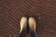 Top view of farmer rubber boots on ploughed arable land