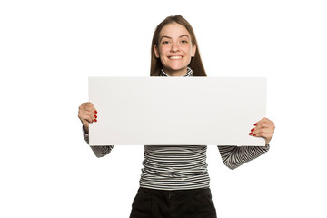 Wall Mural - Young model in blouse shows an empty advertising board on white background