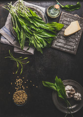 Wall Mural - Food background with ramson, wild garlic, leaves bunch on dark rustic kitchen table with ingredients, top view. Healthy cooking still life. Spring seasonal food. Copy space