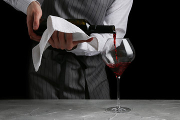 Wall Mural - red wine pouring in glass. bartender on waiter concept on black background