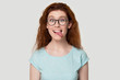 Funny red-haired girl in glasses play childish showing tongue