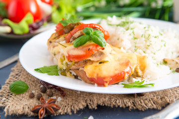 Chicken fillet baked in cheese with rice and vegetables. Fired cordon bleu chicken served with rice and parsley on plate