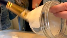 Closeup Of A Woman Painting A Glass Jar With White Acrylic Paint To Use It As Vase In An Upcoming Wedding