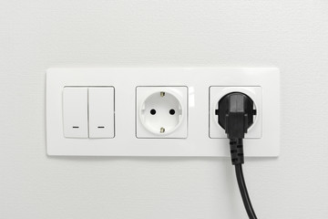 Wall Mural - Electrical sockets on the wall with black connection plug and white switch.