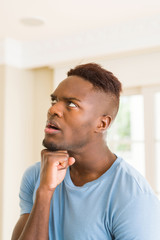 Canvas Print - Handsome young african man thinking and questioning with pensive face, hand on chin wondering about a doubt