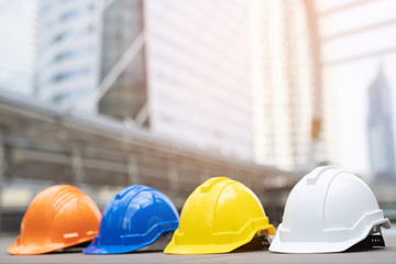 orange, yellow, blue and white hard safety wear helmet hat in the project at construction site building on concrete floor on city. helmet for workman as engineer or worker. concept safety first