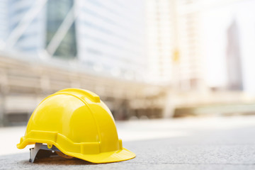 yellow hard safety wear helmet hat in the project at construction site building on concrete floor on city with sunlight. helmet for workman as engineer or worker. concept safety first. 