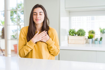 Poster - Beautiful young woman wearing yellow sweater smiling with hands on chest with closed eyes and grateful gesture on face. Health concept.