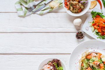 Food assortment on white wooden table top view. Restaurant buffet serving. Plates with healthy breakfast meals.