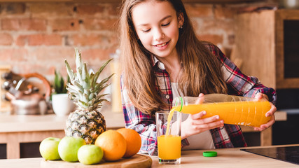 Child health and development. Vitamin orange juice for balanced nutrition. Little girl pouring fresh fruit drink from bottle.