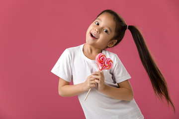 Wall Mural - Beautiful smiling little child girl with sweet candy lollipop isolated on pink background