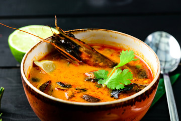 Wall Mural - Hot seafood soup with fish, shrimps and clams on dark table