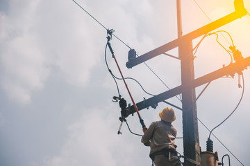 The power lineman use clamp stick (insulated tool) to closing a transformer on energized high-voltage electric power lines. The power lineman must be trained because it is a risky job.