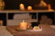 © New Africa - Burning candles and aromatic reed freshener on table in spa salon