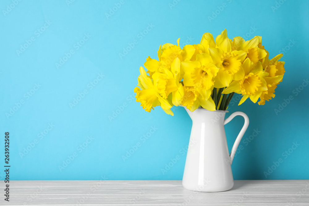 Bouquet of daffodils in jug on table against color background, space for text. Fresh spring flowers - obrazy, fototapety, plakaty 